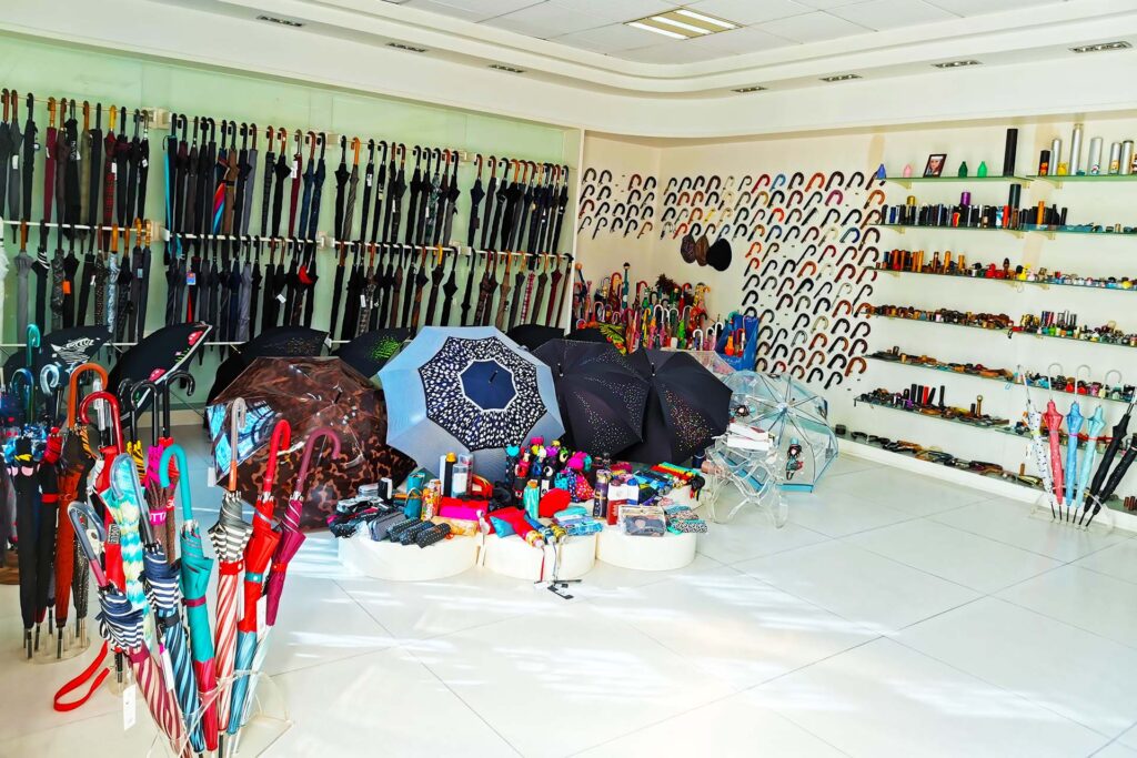 Umbrella showroom with long umbrellas on wall racks, rows of curved handles and open umbrellas on display